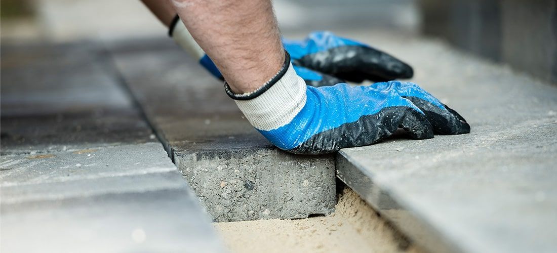 Builder in work gloves laying new pavement.