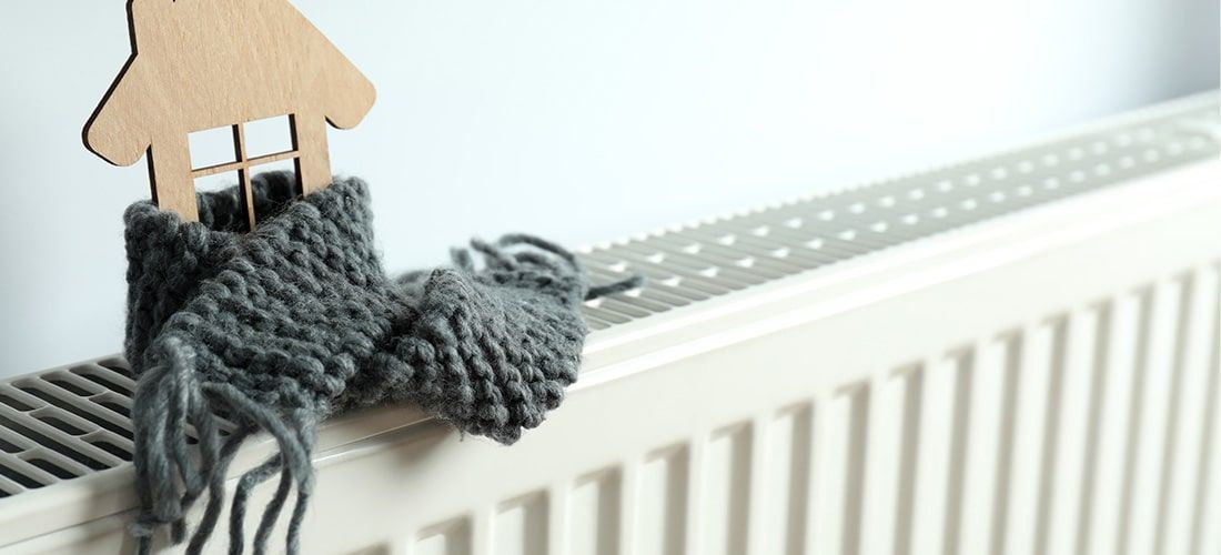 model home atop radiator with a scarf wrapped around it.