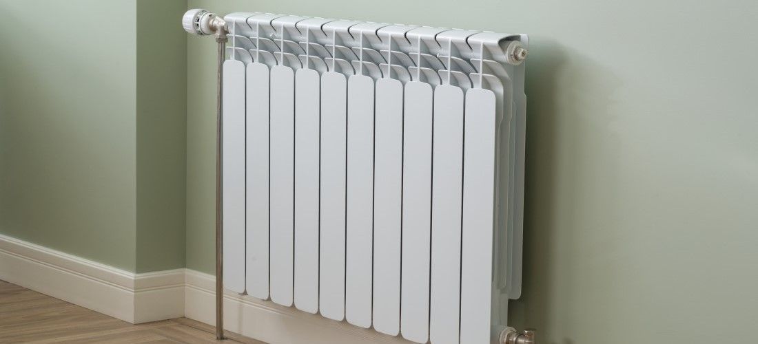 White radiator on light green wall.