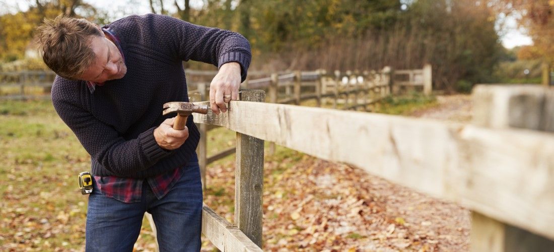 Homeowner repairing damaged fence.