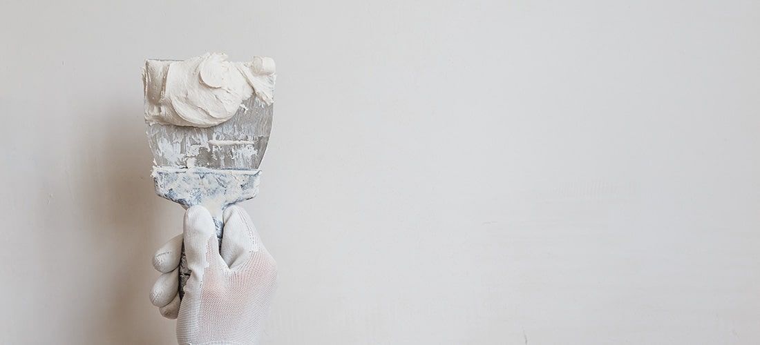 Worker with white glove plastering a wall.