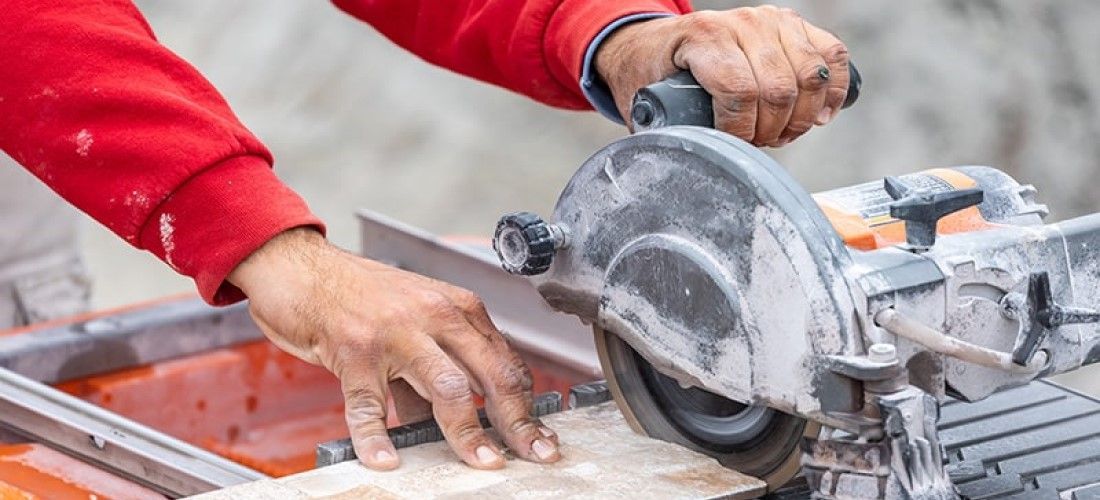 Worker using wet tile saw to cut tiles.