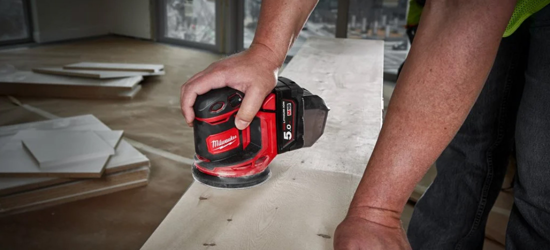 Tradesperson using Milwaukee sander.