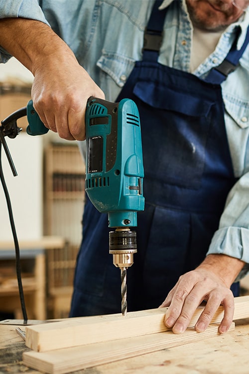 Carpenter drilling fixing hole with heavy-duty power saw.