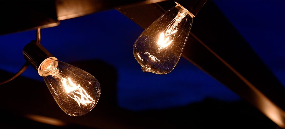 Closeup of a string of lightbulbs hung on pergola.