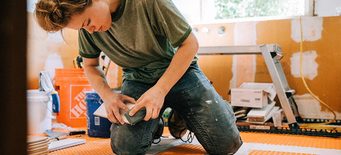 Worker smoothing subway tile with sanding block.