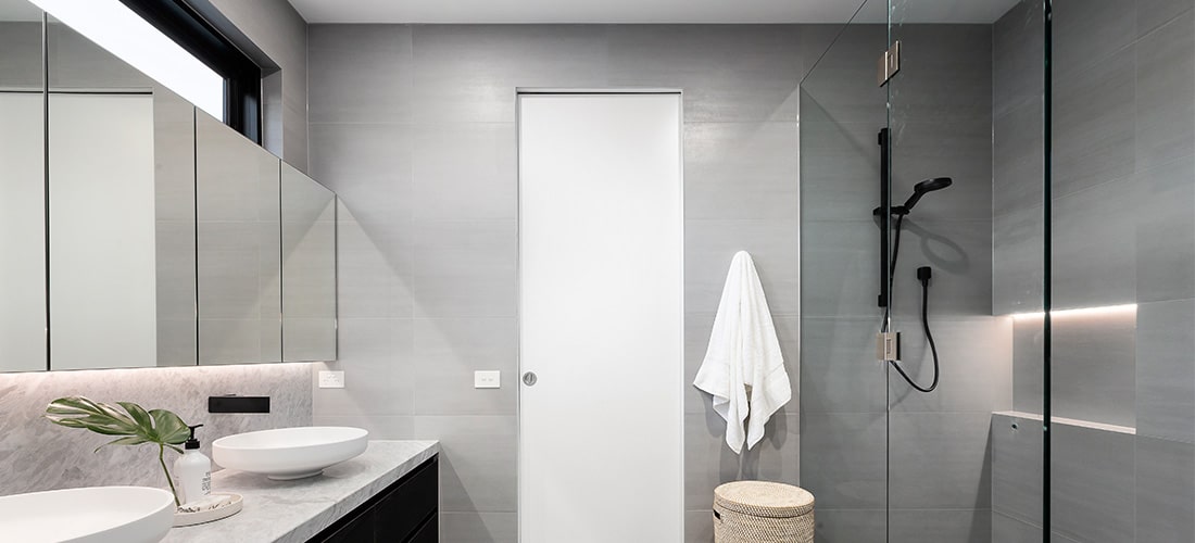 Grey bathroom with twin sinks and bright lighting.