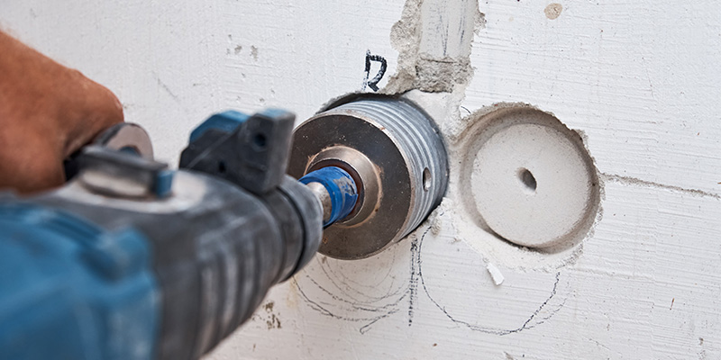 Worker drilling into masonry with a diamond core drill.