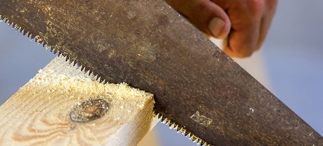 Carpenter cutting wooden board with a panel saw.