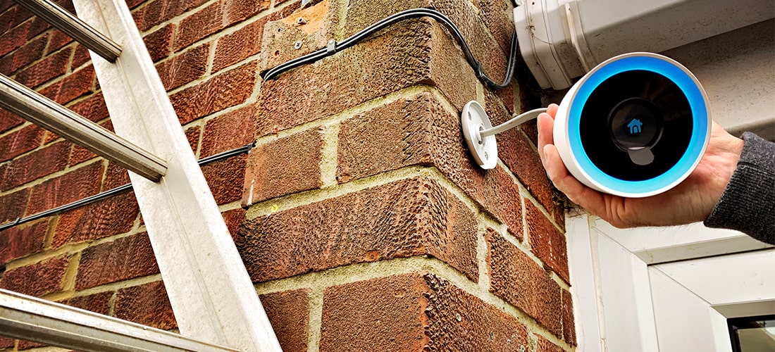 Engineer installing security camera above front door.