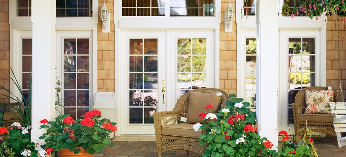 Bright front decking with colourful flowers and well kept French doors.