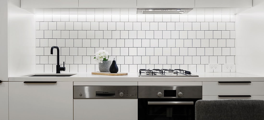 Modern Kitchen with new appliances and white tiled wall.