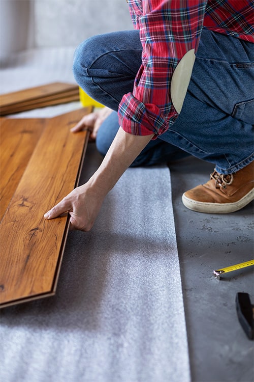 Worker installing new laminate flooring.