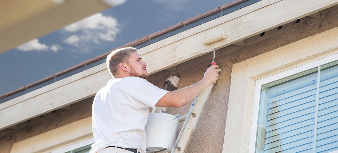 Proffesional painter on a ladder painting fascia.