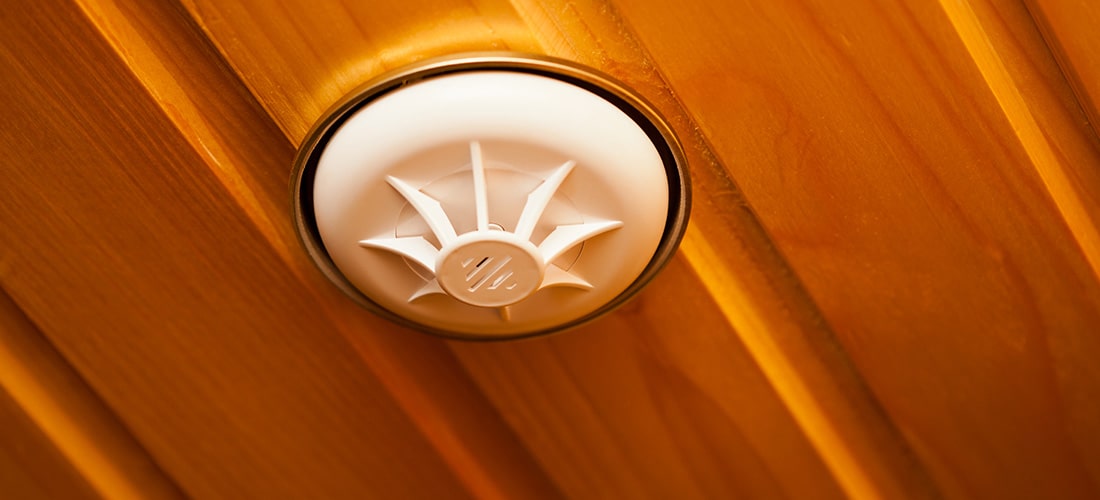 Smoke detector installed into wooden ceiling.