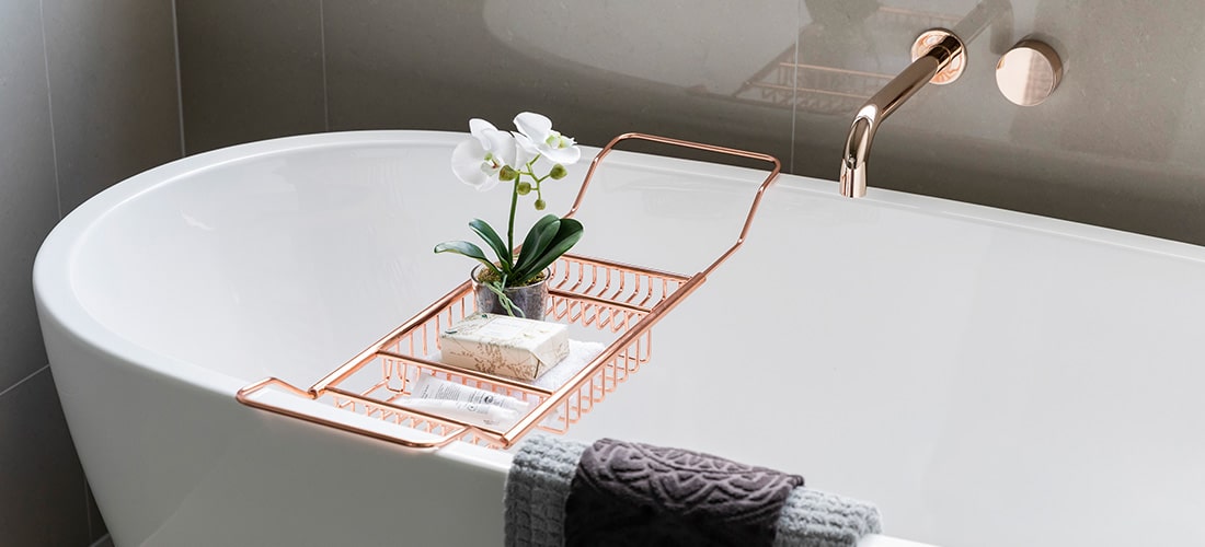 Luxury bathtub with golden taps and wire rack. 