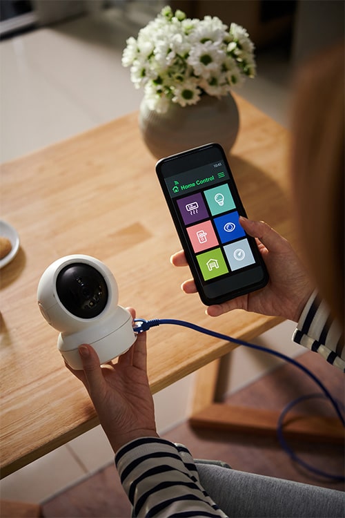 Woman connecting smartphone with security camera.