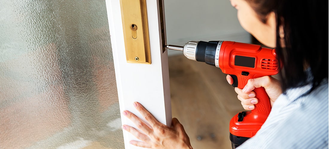 Woman using power drill to install a door.