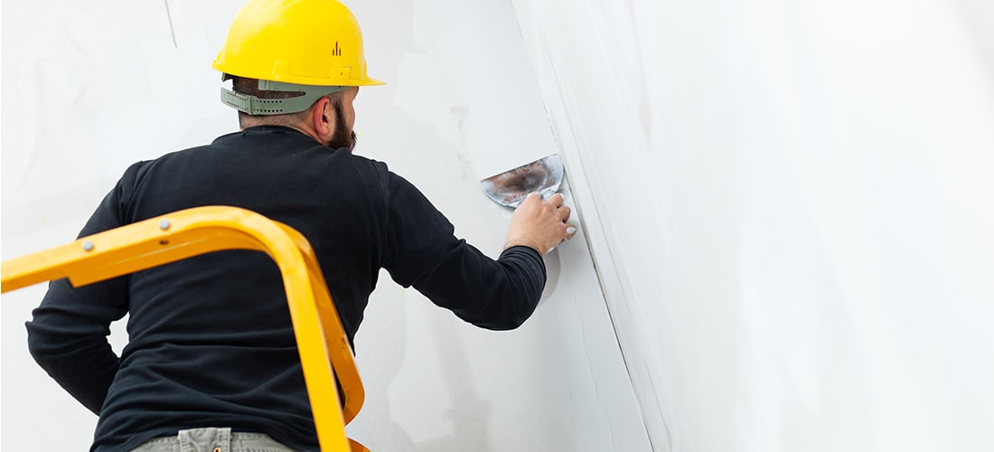 Worker in hardhat plastering a wall.